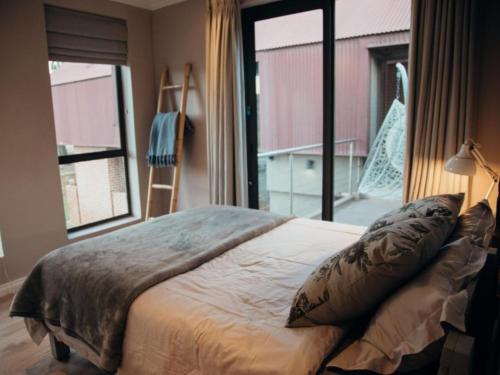a bedroom with a bed and a large window at Sensiri Myst Country House in Dullstroom