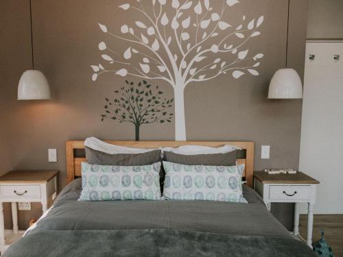 a bedroom with a bed with a tree stencil on the wall at Sensiri Myst Country House in Dullstroom