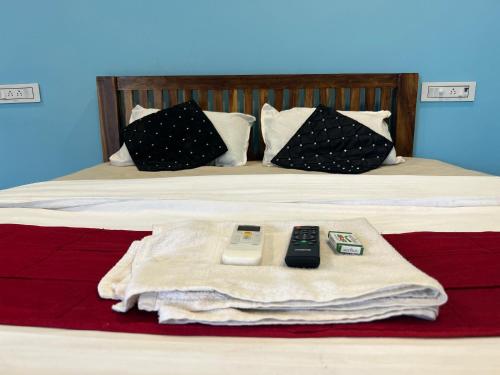 a bed with two remote controls and a blanket at Selvas Eden Resort with river view near boat house in Puducherry