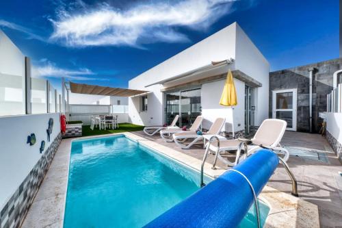 een zwembad met stoelen en een glijbaan bij Villa Cassia - Private Pool, Foosball, BBQ, Air-Con and SAT Tv By Lanzarote Vacation Homes in Playa Blanca