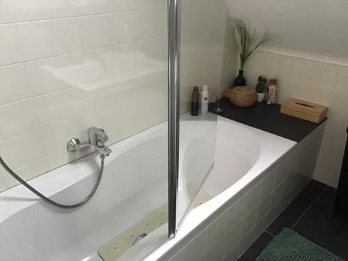 bañera blanca con puerta de ducha de cristal en Sunny dunes en Zandvoort