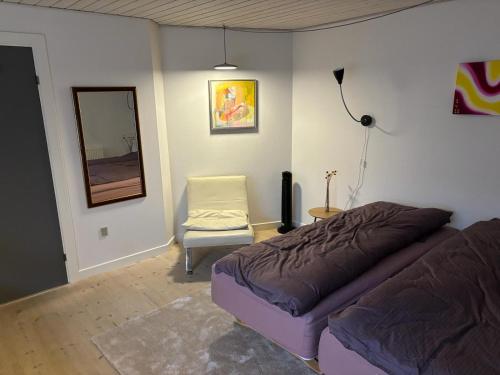een slaapkamer met een bed en een stoel bij Vroldvej in Skanderborg