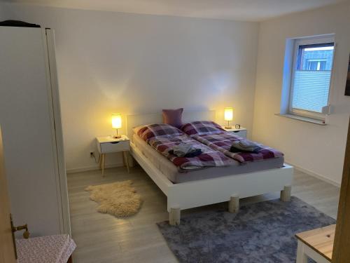 1 dormitorio con 1 cama, 2 lámparas y ventana en Ferienwohnung Kleinbreitenbach en Plaue