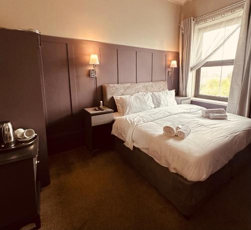 a bedroom with a large bed with two slippers on it at Queensmead Hotel in Shanklin