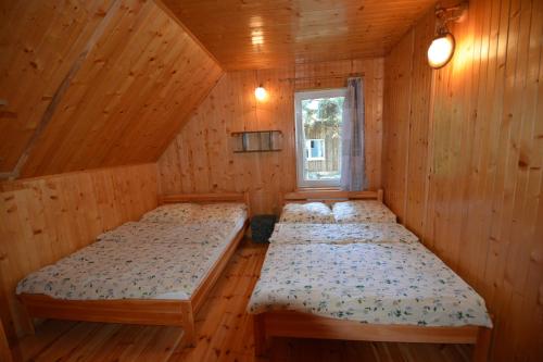 two beds in a wooden room with a window at Domyletnie Pobierowo Dom 100m2 z własną działka in Pobierowo