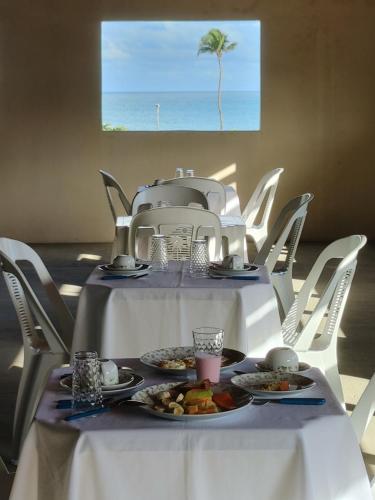 Pousada Viva Praia في باراكورو: طاولة بيضاء عليها صحون طعام