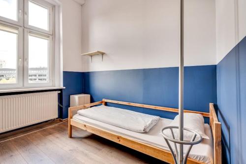 a bed in a room with a blue wall at Hostel Kattowitz in Katowice