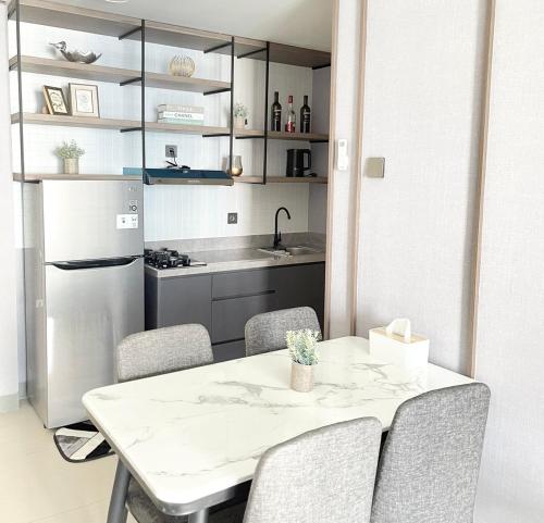 a kitchen with a table and chairs and a refrigerator at 2 BR I ANDERSON I 18floor I above pakuwon mall I the biggest shopping center in Surabaya