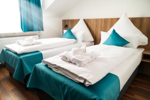 two beds in a hotel room with blue pillows at Hotel Hansa Stuttgart City in Stuttgart