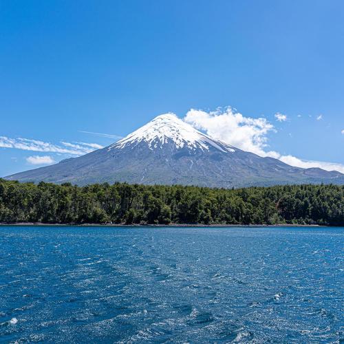 a snow capped mountain in front of a body of water at Cabañas Estrella del Sur in Puerto Varas