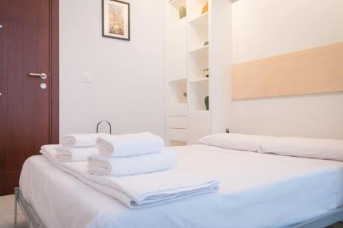 a white room with two beds with towels on top at Apartamento nuevo junto a la Catedral de Sevilla in Seville