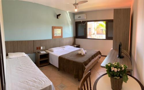 a hotel room with two beds and a table at Ferrujão Pousada e Restaurante in Garopaba