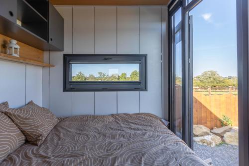 1 dormitorio con 1 cama y TV en la pared en Les Tiny du Pré Mathy - Logements insolites avec Jacuzzi à Profondeville, en Profondeville