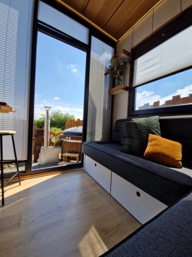 a living room with a couch and large windows at Les Tiny du Pré Mathy - Logements insolites avec Jacuzzi à Profondeville in Profondeville