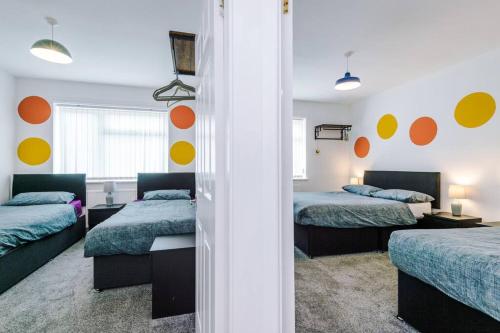 two beds in a room with orange and yellow circles on the wall at Seaside Serenity: Coastal Charm in Rhyl