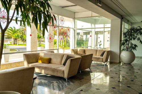 a lobby with couches and plants in a building at Golden Tulip Président Hammamet in Hammamet