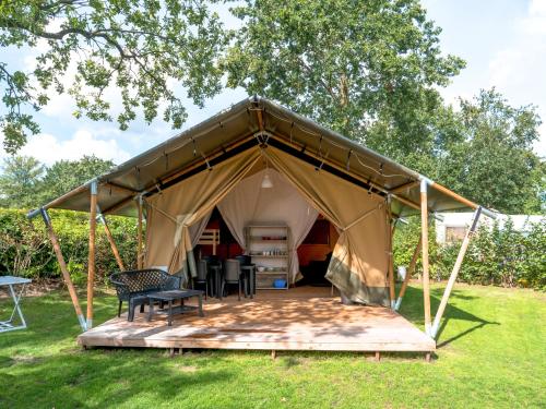 a tent with a wooden deck in the grass at Boerderijcamping de Berghoeve in Ruinen