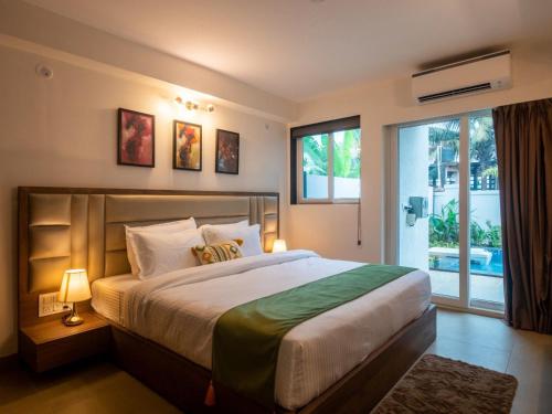 - une chambre avec un grand lit et une grande fenêtre dans l'établissement Jade 4BHK Private Pool Villa by Le Pension Stays, à Vieux-Goa