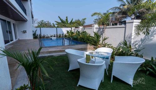 a patio with a table and chairs and a swimming pool at Jade 4BHK Private Pool Duplex by Le Pension Stays in Old Goa