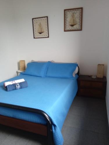 a blue bed in a room with two pictures on the wall at Suíte casal 5min a pé da praia da Enseada in Guarujá
