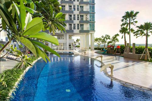a swimming pool in front of a tall building at 2 BR I ANDERSON I 18floor I above pakuwon mall I the biggest shopping center in Surabaya