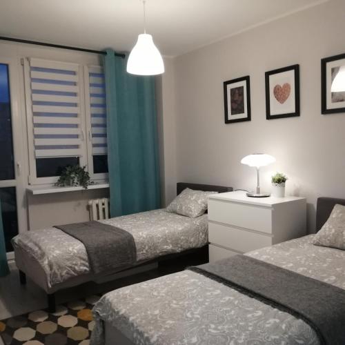 a bedroom with two beds and a table with a lamp at Apartament Classic Południe in Włocławek