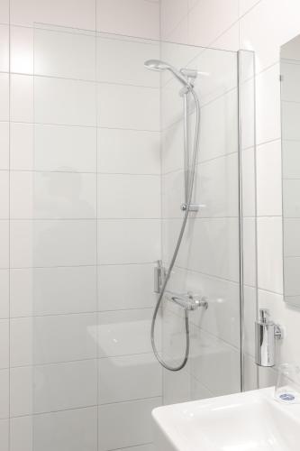 a white bathroom with a shower and a sink at Fletcher Hotel Paleis Stadhouderlijk Hof in Leeuwarden