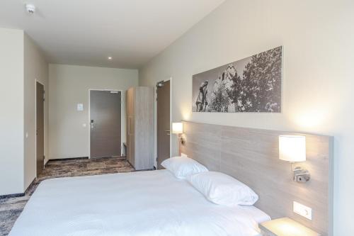 a bedroom with a large white bed with two pillows at Fletcher Hotel Paleis Stadhouderlijk Hof in Leeuwarden