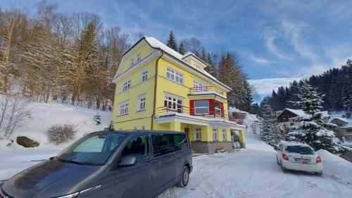 una furgoneta estacionada frente a una casa amarilla en Villa Weber Apartments en Albrechtice v Jizerských horách