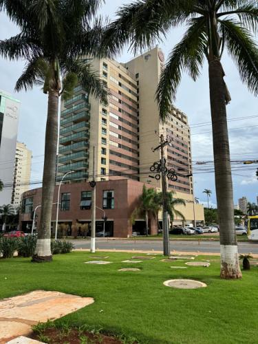 a park with palm trees in front of a building at Lindo Flat Particular decorado in Brasilia