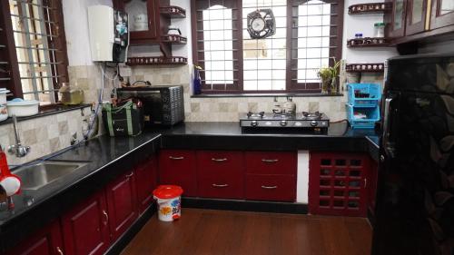 a kitchen with red cabinets and a black counter top at Honey Paradise Homestay in Trivandrum