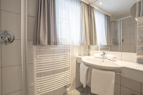 a white bathroom with a sink and a mirror at Petit Madlein in Ischgl