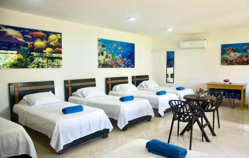 a group of four beds in a room at HOTEL CASA BLANCA in Necoclí