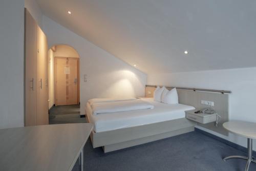 a white bedroom with a bed and a table at Petit Madlein in Ischgl