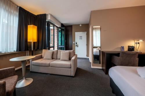 a hotel room with a bed and a couch and a table at Hotel Docklands Antwerpen in Antwerp