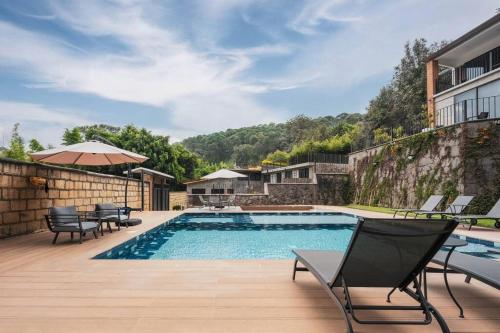 a swimming pool with chairs and an umbrella next to a building at La Fábrica #8 Canfranc in Valle de Bravo