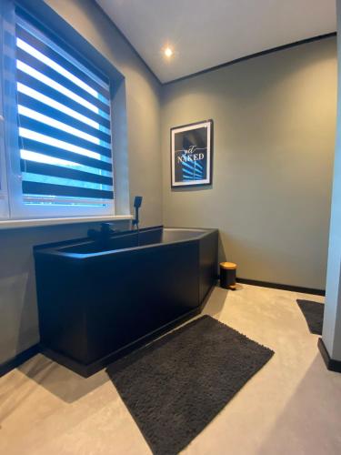 Le Ravel Maison في بورج ريولاند: حوض استحمام أسود في غرفة مع نافذة