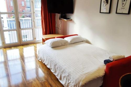 een wit bed in een kamer met een groot raam bij Spacious City Centre Apt - O'Connell Street Area in Dublin