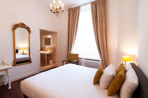 a bedroom with a large white bed and a mirror at Hotel Schimmelpenninck Huys in Groningen