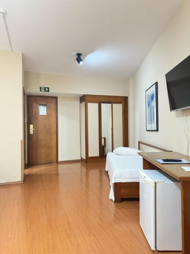 a bedroom with a bed and a desk and a television at César Park Hotel in Juiz de Fora