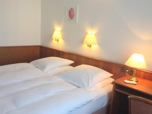 - un lit avec 2 oreillers blancs et 2 lampes dans l'établissement Hotel Bismarck, à Düsseldorf