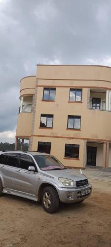 a silver suv parked in front of a building at ROZERA Gardens Hotel in Rukungiri