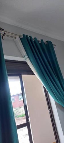 a window with a green curtain in a room at ROZERA Gardens Hotel in Rukungiri