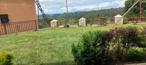 a yard with a fence and a field of grass at ROZERA Gardens Hotel in Rukungiri