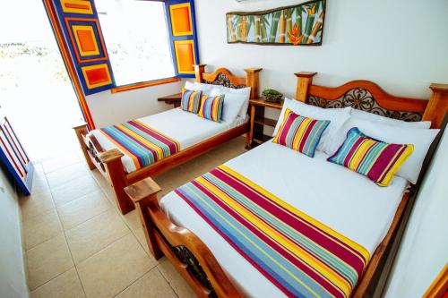 a bedroom with two beds with colorful pillows at Finca Nuevo Monarca in Pereira
