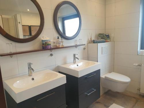 een badkamer met 2 wastafels, een spiegel en een toilet bij ROSE'S Ferienwohnung in Bernbach