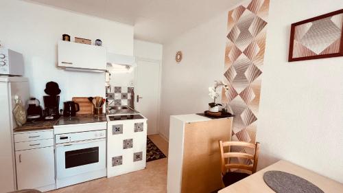 Il comprend une petite cuisine équipée d'une cuisinière blanche et d'un comptoir. dans l'établissement Les Joncs, T2 lumière et mer, à Saint-Hilaire-de-Riez