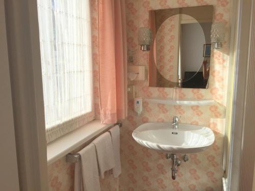ein Badezimmer mit Waschbecken und Spiegel in der Unterkunft Hotel Bismarck in Düsseldorf