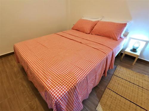 a bed with an orange and white checkered blanket at Edy's STD04 in Imsouane