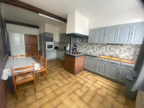 une cuisine avec des armoires blanches et une table à l'intérieur dans l'établissement Maison calme, au Tréport